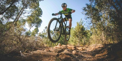Mountainbiker springt mit Mountainbike durch den Wald