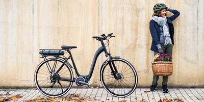 Frau steht neben ihrem E-Bike