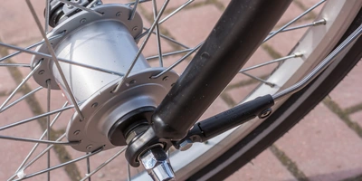 Nabendynamo nachrüsten - so geht's Nahaufnahme des Fahrradnaben mit Speichen, Achse und Nabendynamo auf einem Pflastersteinboden.