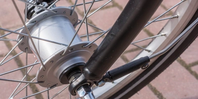 Detailaufnahme eines Fahrradnaben mit Speichen und Gabel auf gepflastertem Boden.