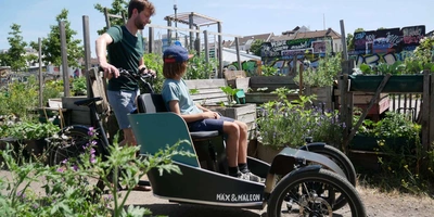 Mann mit Kind und Lastenrad in einem Feld