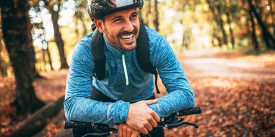 Mann mit Fahrrad und Helm mit herbstlichem Hintergrund