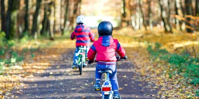 Kinder fahren Fahrrad mit herbstlichem Hintergrund