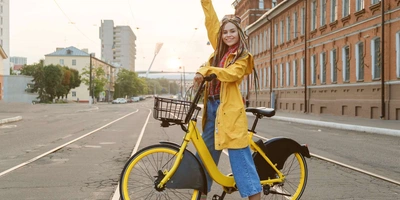 Eine Frau sitzt auf einem Fahrrad und hebt die Hand.