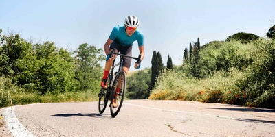 Rennradfahrer mit Helm fährt Strasse runter.