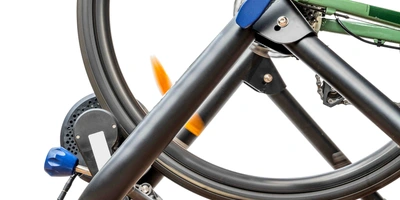 Der Rollentrainer – eine gute Alternative bei schlechtem Wetter? Rollentrainer mit eingespanntem Rennrad vor weißem Hintergrund