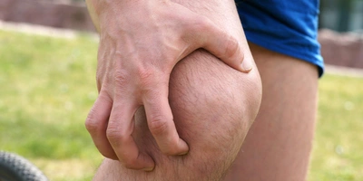 Person hält sich das Knie beim Radfahren