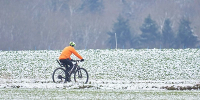 Kann bei Schnee mit dem Fahrrad gefahren werden? Fahrradfahrer fährt im Schnee