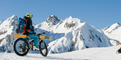 Ein E-Bike Fahrer fährt im Schnee mit seinen Skiern