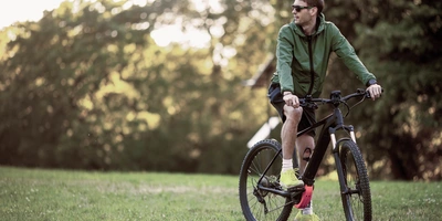 Wendiges und leichtes Premium E-Bike Mann steht mit Fahrrad auf einer Wiese