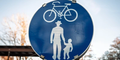 STVO Fahrrad Österreich - das gilt Blaues Straßenschild mit einem weißen Fahrrad und einem Erwachsenem mit Kind
