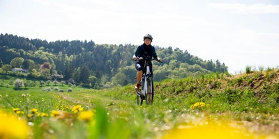 Eine Frau fährt mit dem Fahrrad auf einem Feld.
