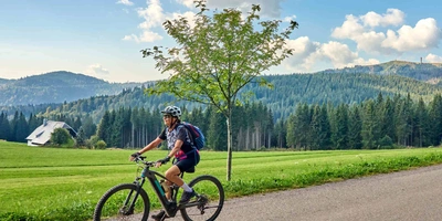 Das Unno Ikki eignet sich sowohl für's Gelände als auch für die Straße. Frau mit Helm fährt mit Mountainbike durch Tal.