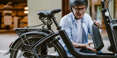 Mann in der Stadt nimmt Akku aus seinem E-Bike raus