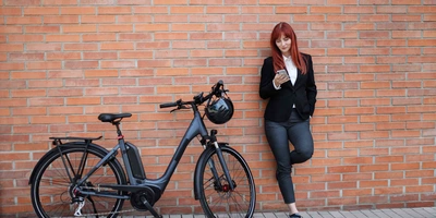 Frau steht neben Fahrrad an Wand