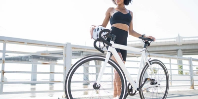 Das neue Chord X ist nicht nur smart sondern auch stylish. Frau steht neben Rennrad vor Geländer von Brücke.