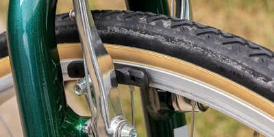 V-Brake einstellen – die Schritt-für-Schritt-Anleitung Nahaufnahme eines Fahrradrads mit einem grünen Rahmen und einem gelben Reifen.