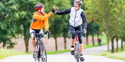 Das Van Rysel E-EDR AF mit Aluminium-Rahmen wiegt nur 14kg. Zwei Rennradfahrer klatschen sich am Ziel ab.