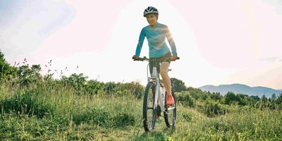 Frau fährt mit Mountainbike über Wiese.