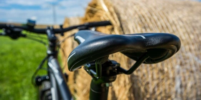 Foto eines Fahrrads, welches an einem Strohballen lehnt, mit Fokus auf den Fahrradsattel