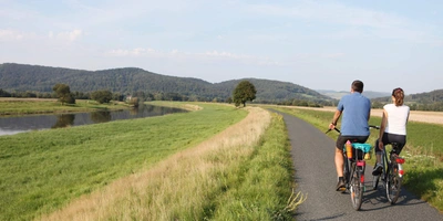 Landschaft des Weserradwegs Personen fahren auf Radweg