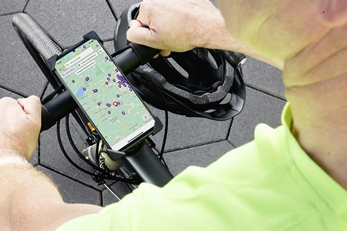 Radfahrender blickt auf Karte mit Bike Services auf Smartphonedisplay