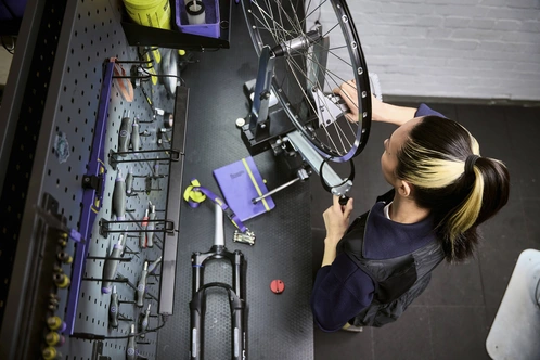 Eine Person arbeitet an einem Fahrradreifen in einer gut ausgestatteten Werkstatt.