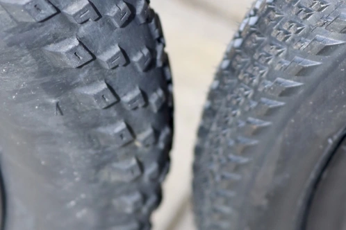 Zwei Fahrradreifen mit unterschiedlichem Profil, einer griffig und einer glatt.